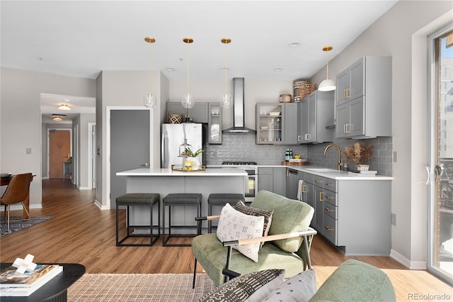 kitchen with gray cabinets, appliances with stainless steel finishes, a center island, and wall chimney range hood