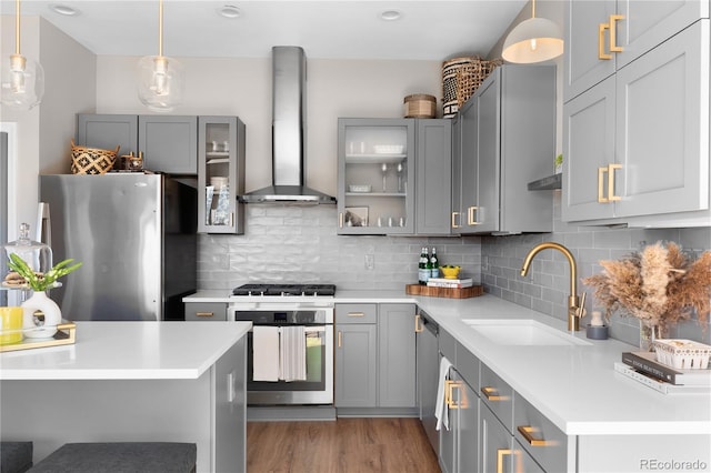 kitchen featuring appliances with stainless steel finishes, pendant lighting, sink, backsplash, and wall chimney exhaust hood