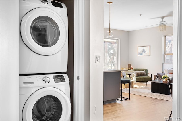 laundry area with ceiling fan, stacked washer / dryer, and light wood-type flooring