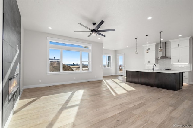 unfurnished living room featuring a large fireplace, a healthy amount of sunlight, and light wood-type flooring