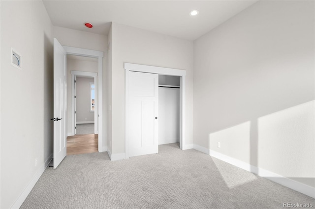 unfurnished bedroom with light colored carpet and a closet