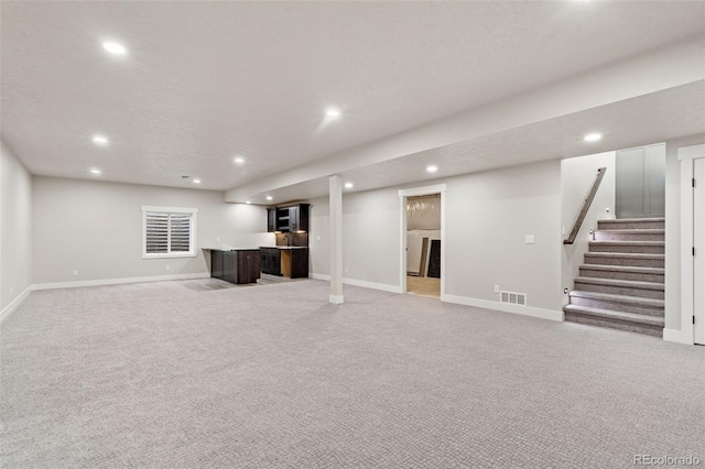 basement featuring light carpet and a textured ceiling