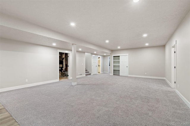 basement featuring light carpet and a textured ceiling