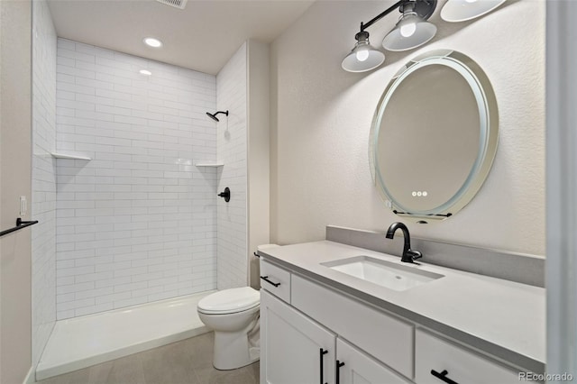 bathroom featuring vanity, tile patterned floors, toilet, and tiled shower