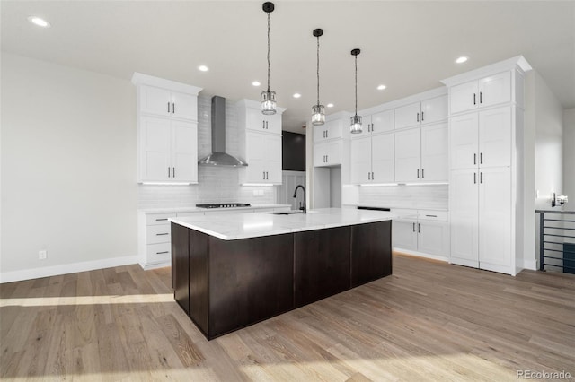 1369 Burt Ave, Berthoud, CO 80513 - kitchen featuring wall chimney range hood, a sink, decorative backsplash, light wood-style floors, and recessed lighting