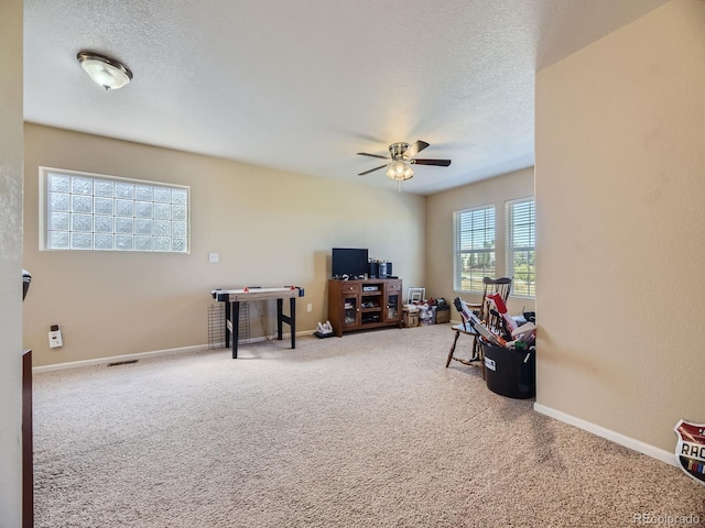 playroom featuring ceiling fan, a textured ceiling, plenty of natural light, and carpet