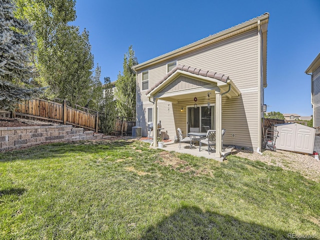 rear view of house with a storage shed, cooling unit, a patio area, and a lawn