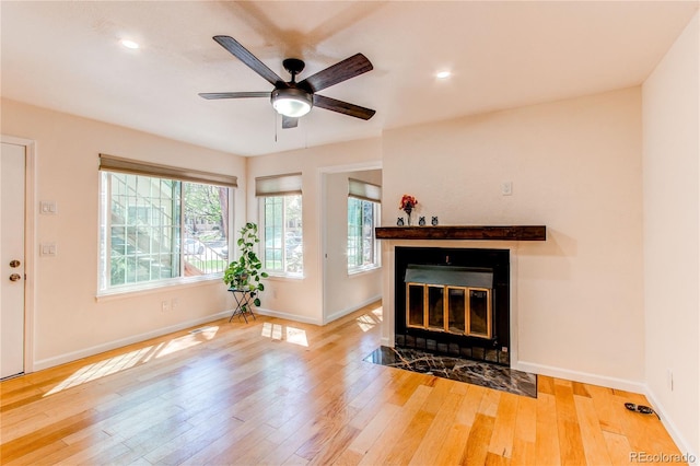unfurnished living room featuring a fireplace with flush hearth, baseboards, hardwood / wood-style floors, ceiling fan, and recessed lighting