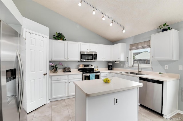 kitchen with a sink, white cabinets, stainless steel appliances, and lofted ceiling