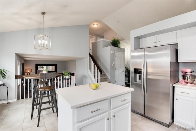 kitchen with light tile patterned floors, lofted ceiling, white cabinets, and stainless steel fridge with ice dispenser