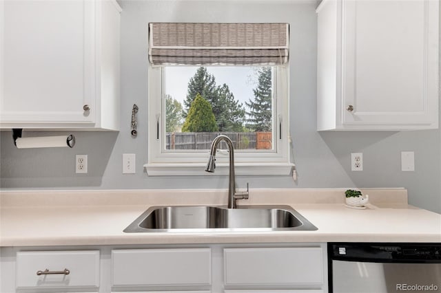 kitchen with stainless steel dishwasher, a sink, white cabinetry, and light countertops