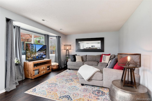 living room featuring visible vents, a textured ceiling, and dark wood-style flooring