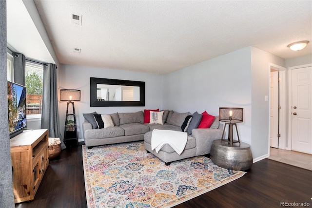 living area with baseboards, a textured ceiling, wood finished floors, and visible vents