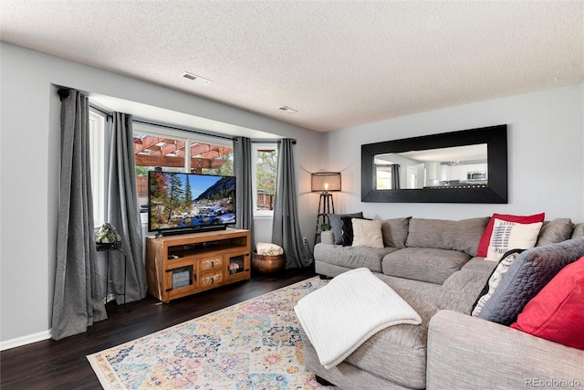 living area featuring baseboards, a textured ceiling, visible vents, and wood finished floors