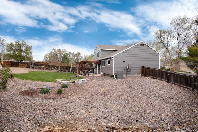 back of house featuring roof with shingles, a fenced backyard, cooling unit, a patio, and a yard