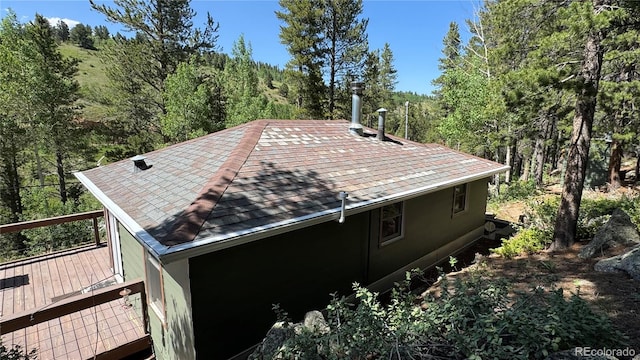 582 Pactolus Lake Rd, Black Hawk, CO 80422 - view of side of home with a shingled roof, a view of trees, and a deck
