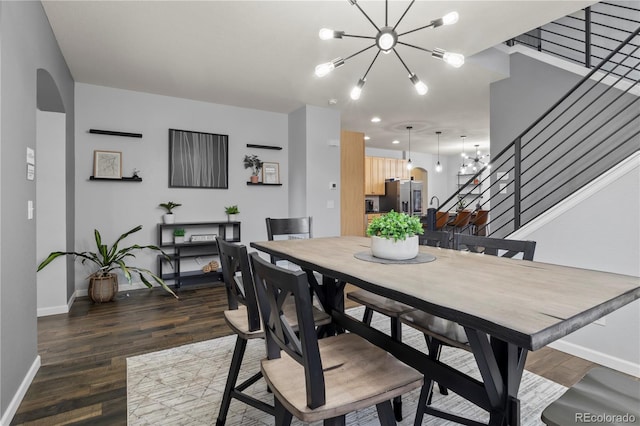 dining area featuring dark wood-type flooring and an inviting chandelier