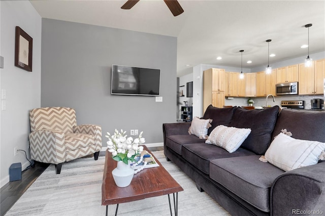 living room featuring ceiling fan, sink, and wood-type flooring