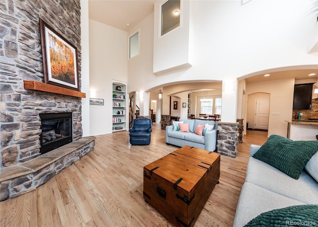 15948 Huckleberry Hts, Colorado Springs, CO 80908 - living area featuring arched walkways, a stone fireplace, wood finished floors, and a towering ceiling