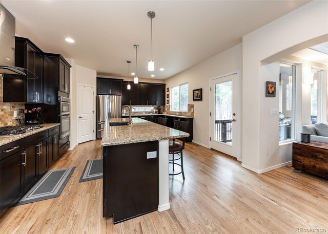 15948 Huckleberry Hts, Colorado Springs, CO 80908 - kitchen featuring wall chimney range hood, tasteful backsplash, a breakfast bar, and stainless steel appliances