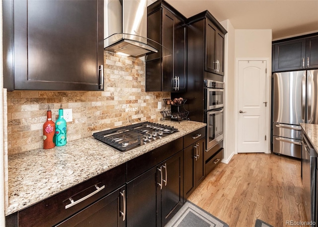 15948 Huckleberry Hts, Colorado Springs, CO 80908 - kitchen featuring decorative backsplash, light stone countertops, light wood-style floors, range hood, and appliances with stainless steel finishes