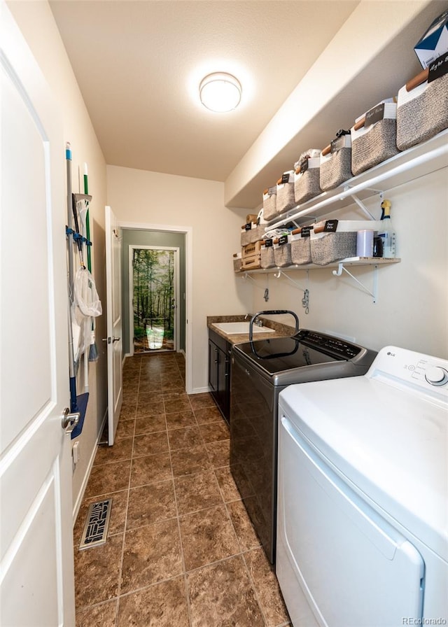 15948 Huckleberry Hts, Colorado Springs, CO 80908 - clothes washing area featuring visible vents, baseboards, washing machine and clothes dryer, a sink, and cabinet space