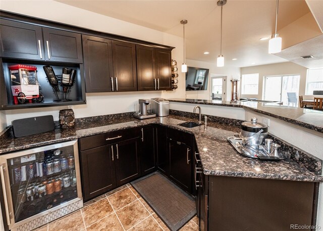 15948 Huckleberry Hts, Colorado Springs, CO 80908 - kitchen with a peninsula, wine cooler, dark stone counters, a sink, and decorative light fixtures