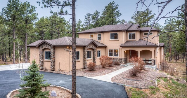 15948 Huckleberry Hts, Colorado Springs, CO 80908 - mediterranean / spanish-style house with stucco siding, a porch, driveway, and stone siding