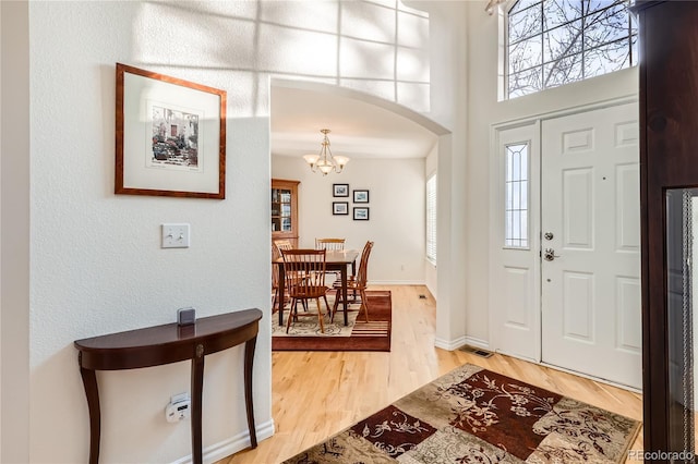 entryway with wood-type flooring and a notable chandelier