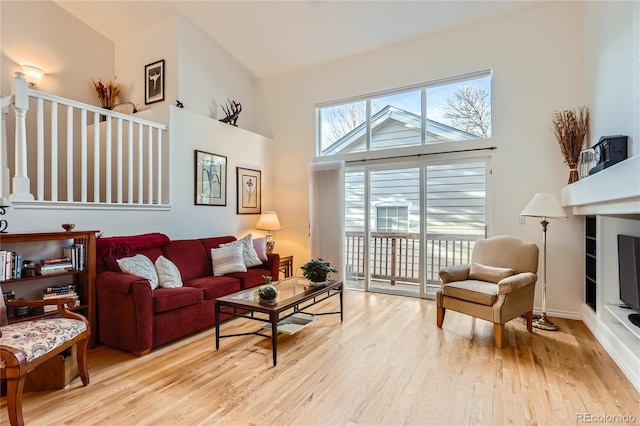 living room featuring high vaulted ceiling and light hardwood / wood-style flooring