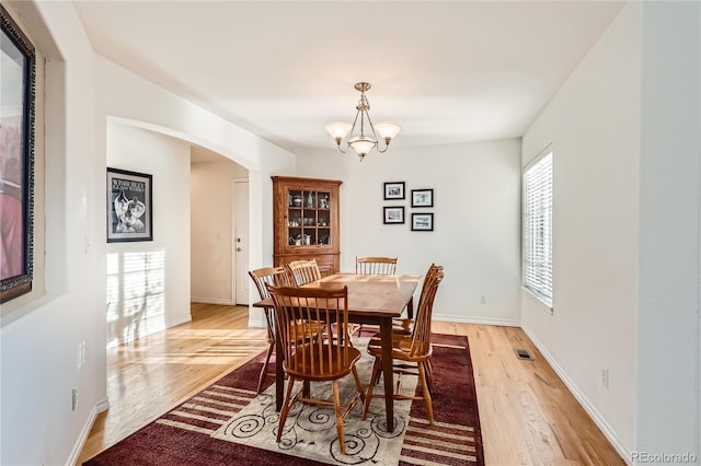 dining space featuring light wood-type flooring and an inviting chandelier