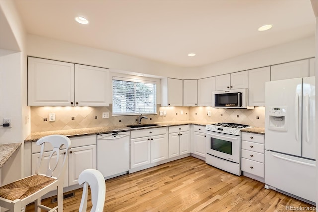 kitchen featuring light stone countertops, sink, white appliances, white cabinets, and light wood-type flooring