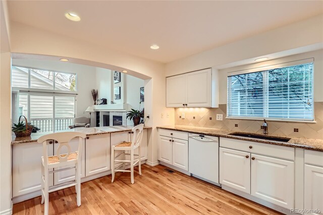 kitchen with stone counters, dishwasher, sink, light hardwood / wood-style floors, and white cabinets