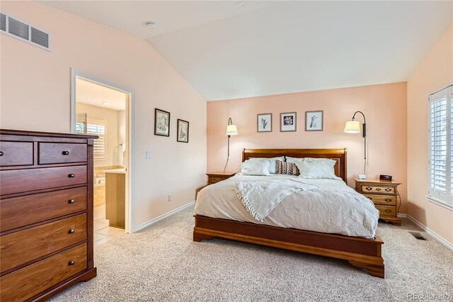 carpeted bedroom featuring ensuite bath and vaulted ceiling