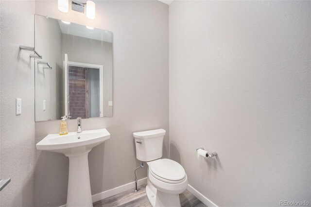 bathroom with baseboards, a sink, wood finished floors, and toilet