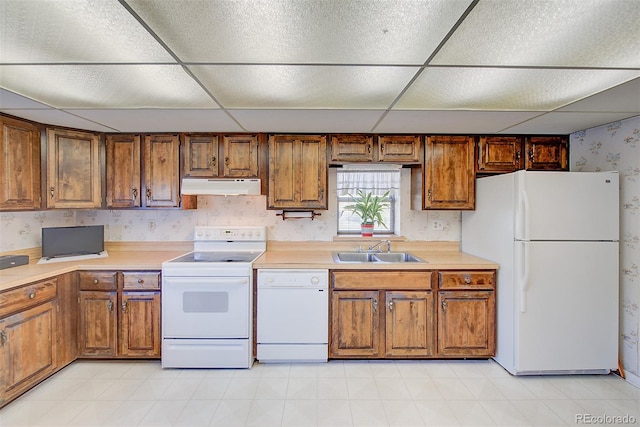 kitchen with a paneled ceiling, white appliances, and sink