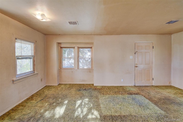 carpeted empty room featuring a textured ceiling