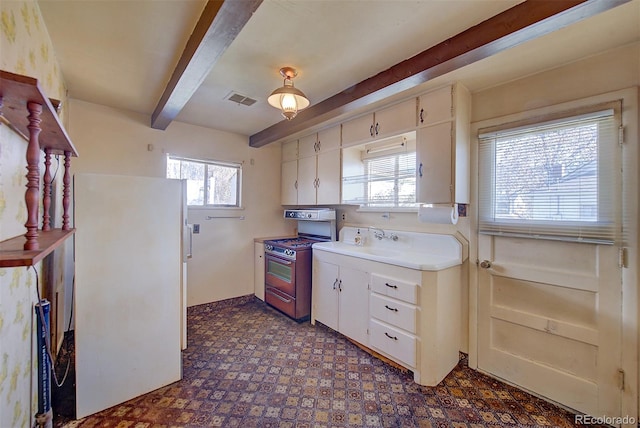 kitchen with sink, beamed ceiling, white fridge, white cabinets, and range