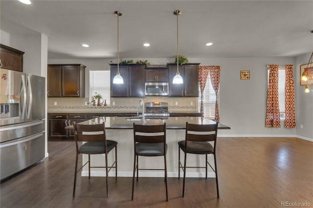 9476 Juniper Way, Arvada, CO 80007 - kitchen featuring appliances with stainless steel finishes, dark brown cabinetry, a kitchen breakfast bar, dark wood-style flooring, and recessed lighting