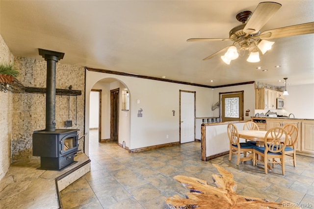 130 Windwalker Rd, Buena Vista, CO 81211 - dining room with a ceiling fan, arched walkways, a wood stove, ornamental molding, and stone tile floors