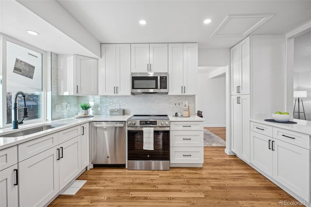 kitchen featuring white cabinetry, appliances with stainless steel finishes, sink, and light hardwood / wood-style flooring