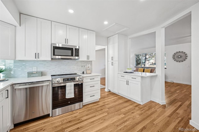 kitchen with white cabinetry, tasteful backsplash, stainless steel appliances, and light hardwood / wood-style flooring