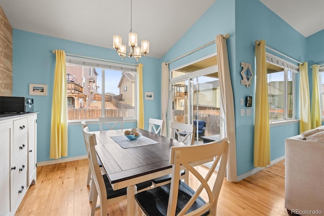 dining area with a chandelier, lofted ceiling, baseboards, and light wood-style flooring