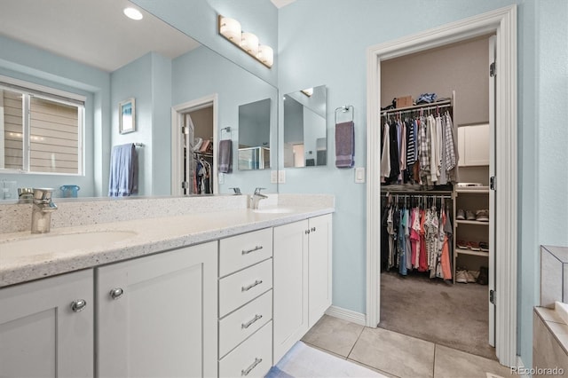 bathroom with double vanity, tile patterned flooring, a walk in closet, and a sink