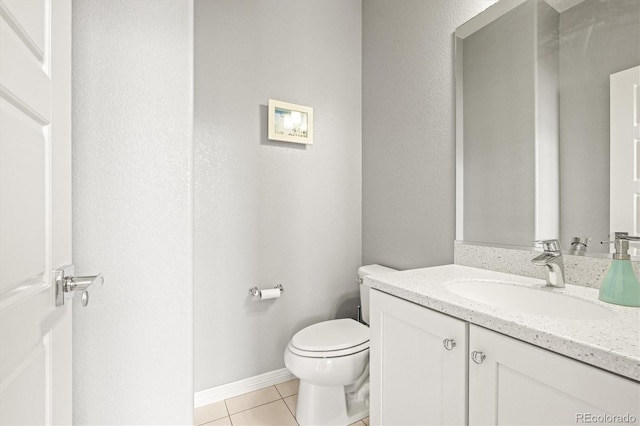 half bath featuring vanity, tile patterned floors, toilet, and baseboards