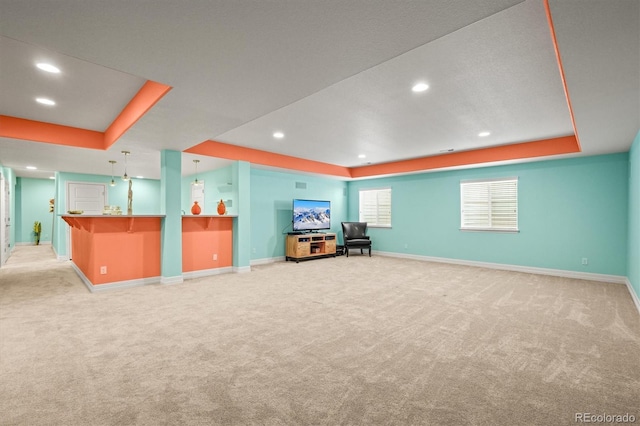 interior space with light carpet, a raised ceiling, and baseboards