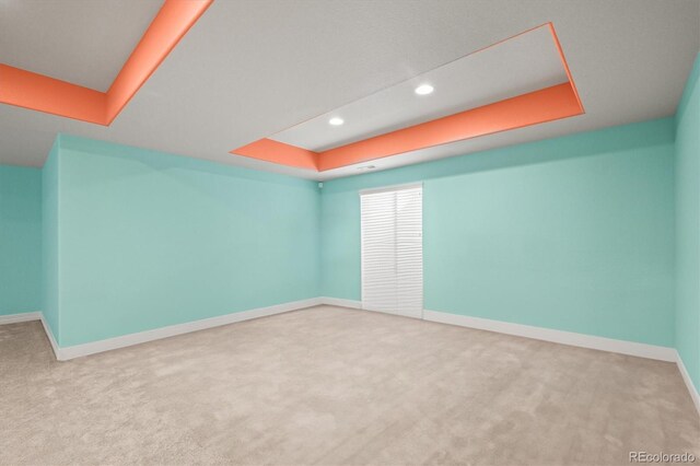 unfurnished room featuring carpet, a raised ceiling, recessed lighting, and baseboards