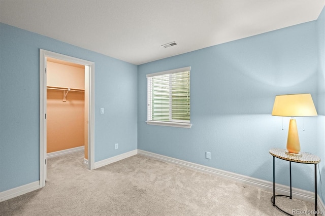 unfurnished bedroom with carpet, visible vents, baseboards, a spacious closet, and a closet