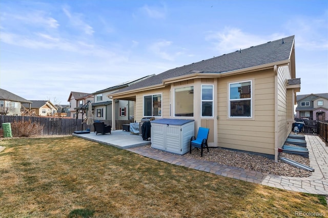 rear view of property featuring a yard, a patio area, a residential view, and a fenced backyard