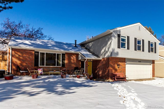 snow covered back of property with a garage